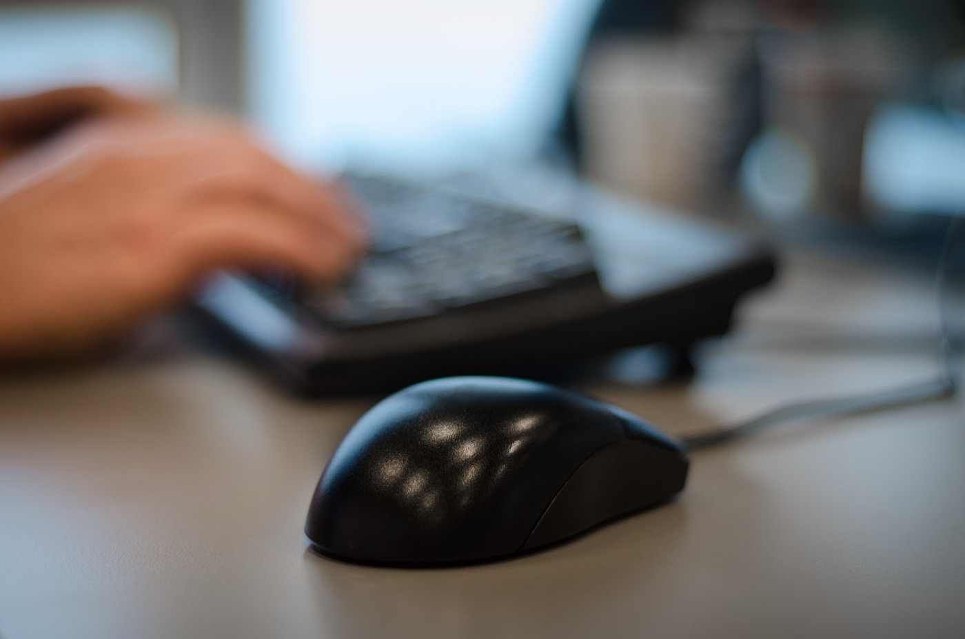 Handen op een toetsenbord aan een bureau