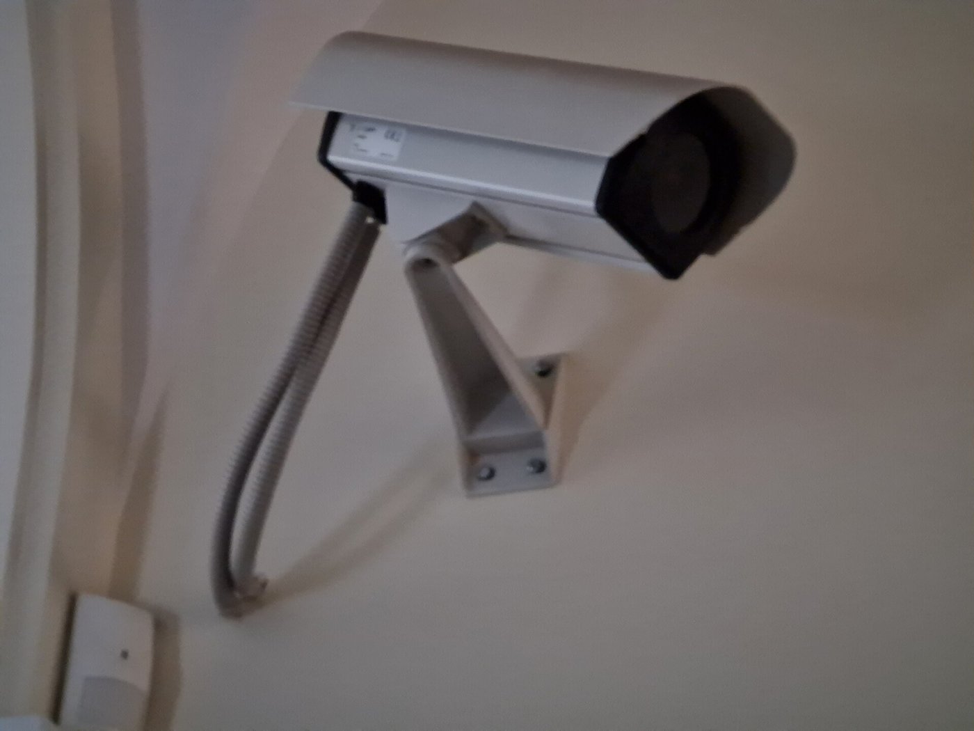 Een beveiligingscamera aan een witte muur, van dichtbij gezien.