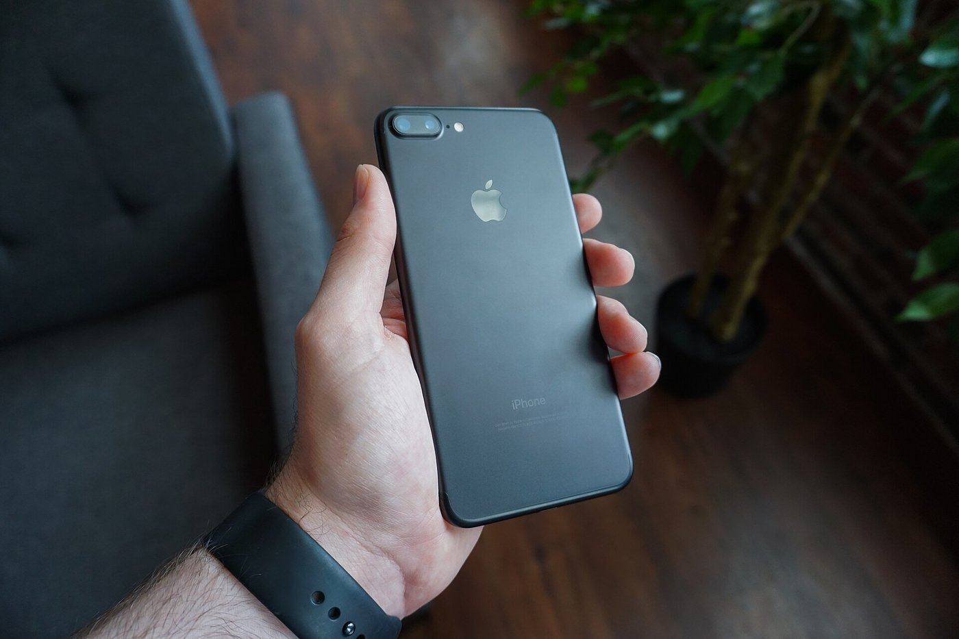 Een hand houdt een zwarte smartphone vast, van bovenaf gezien.