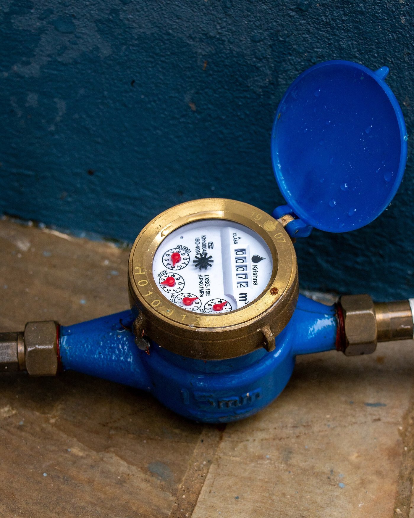 Een watermeter met blauwe leiding en een rode afsluiter.