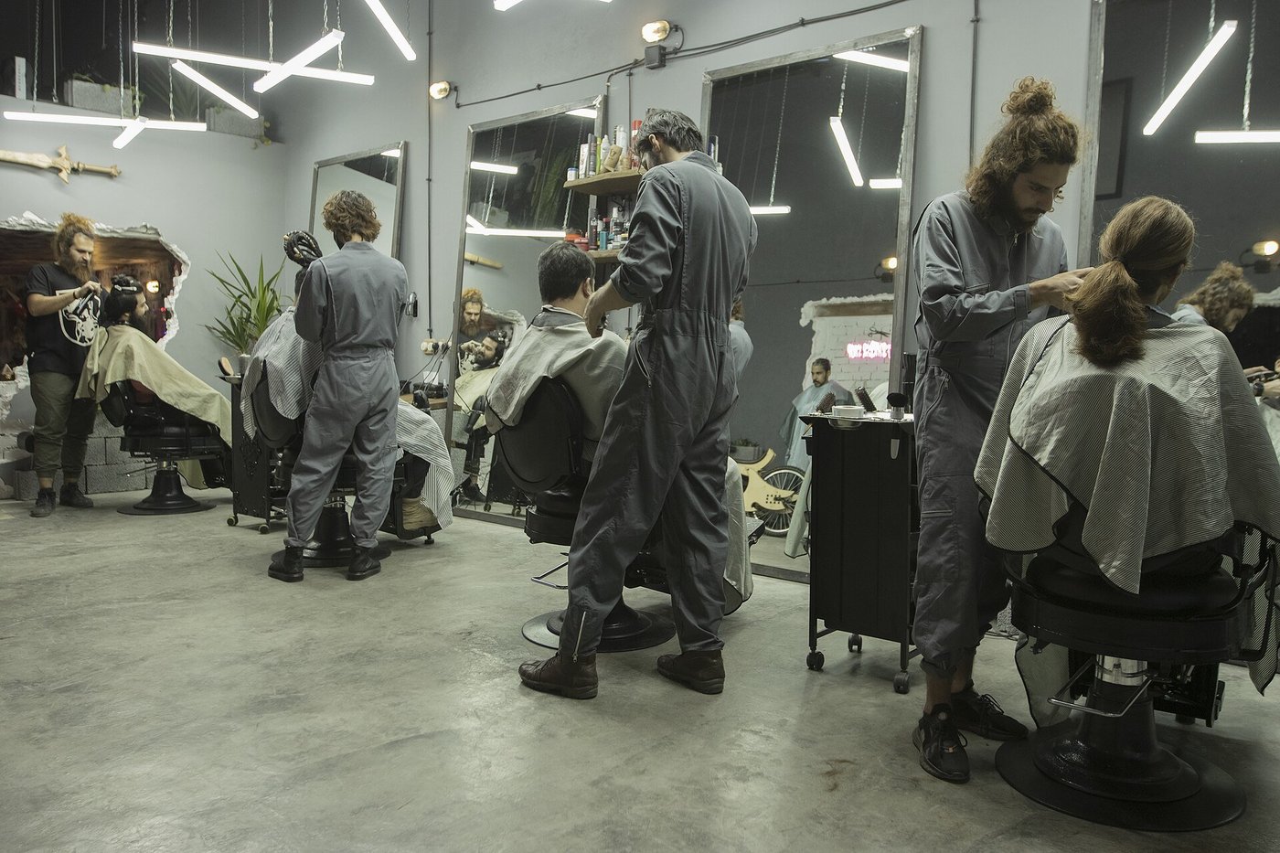 Het interieur van een kapsalon met stylisten aan het werk en klanten in de stoelen.