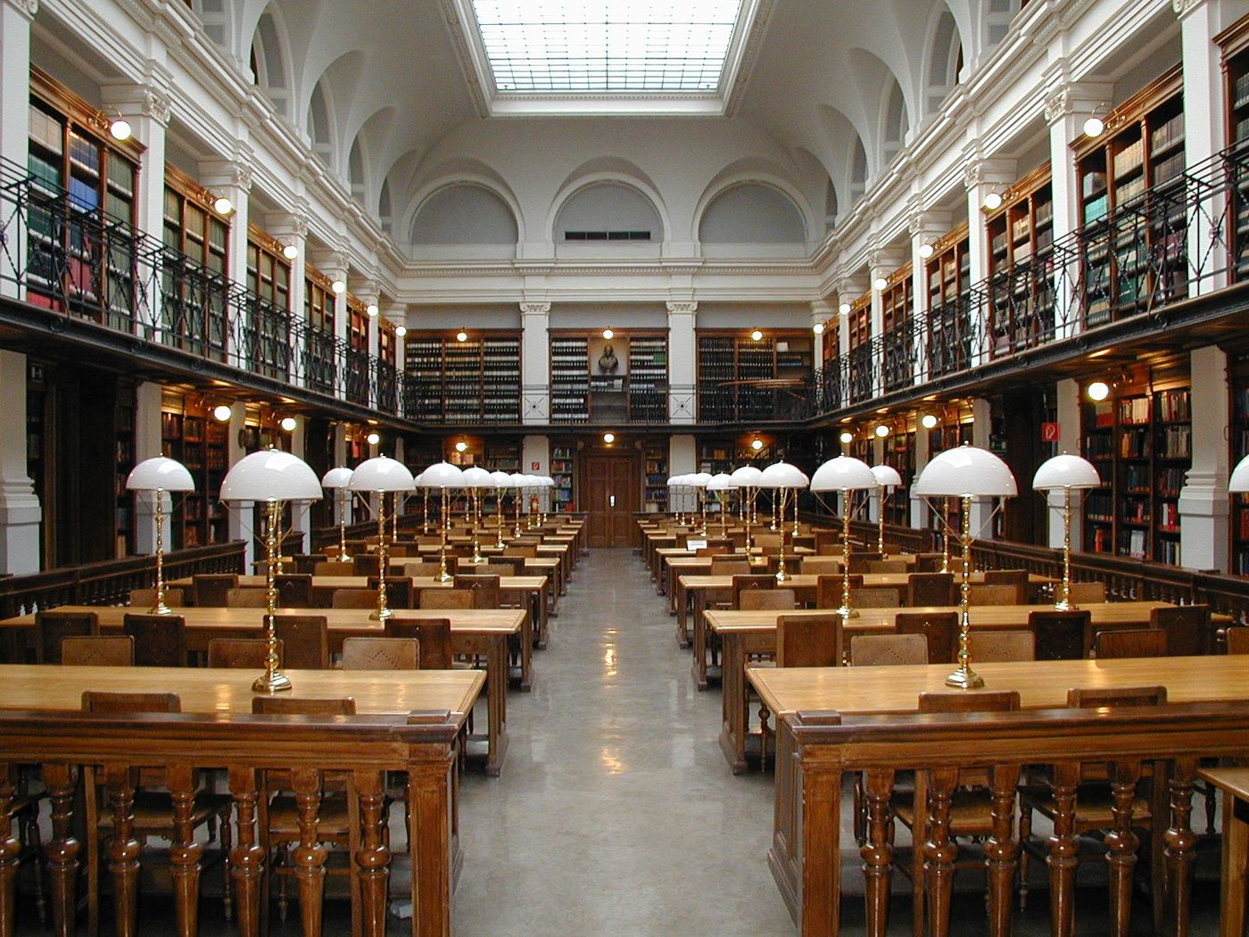 Een klassieke leeszaal van een universiteitsbibliotheek met lange tafels en boekenkasten.