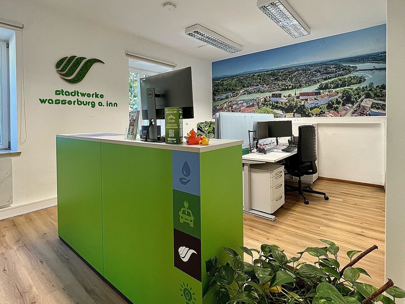 Een klantenservicebalie van een nutsbedrijf met een medewerker achter de computer.