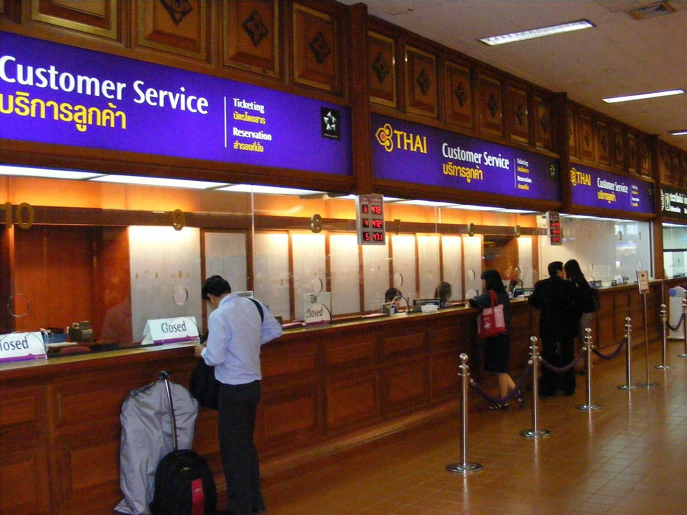 Een klantenservicebalie met wachtende reizigers op een luchthaven.