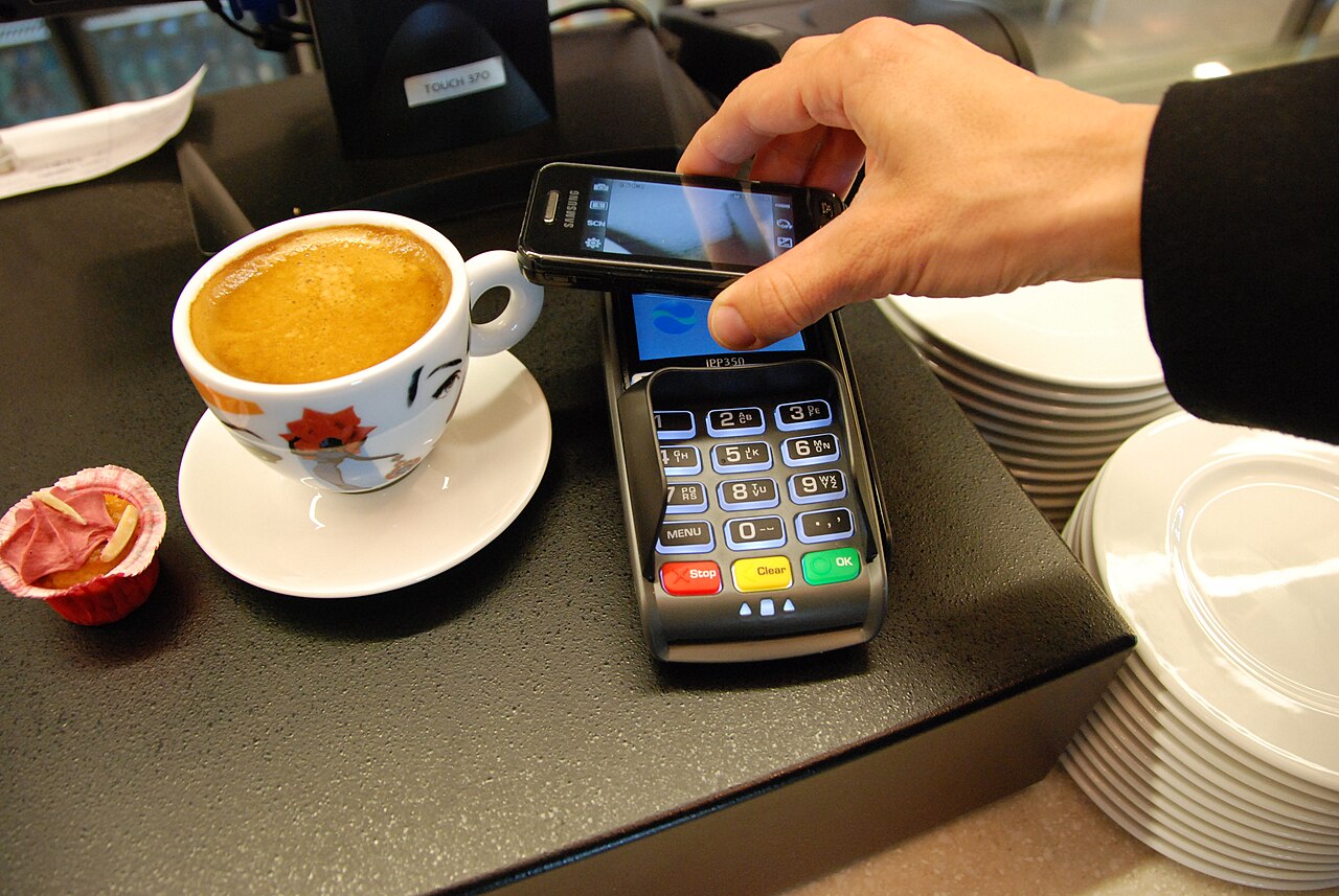 Een betaalterminal aan een toonbank met een smartphone ernaast, de plek waar een loyaliteitsapp aan de kassa punten registreert