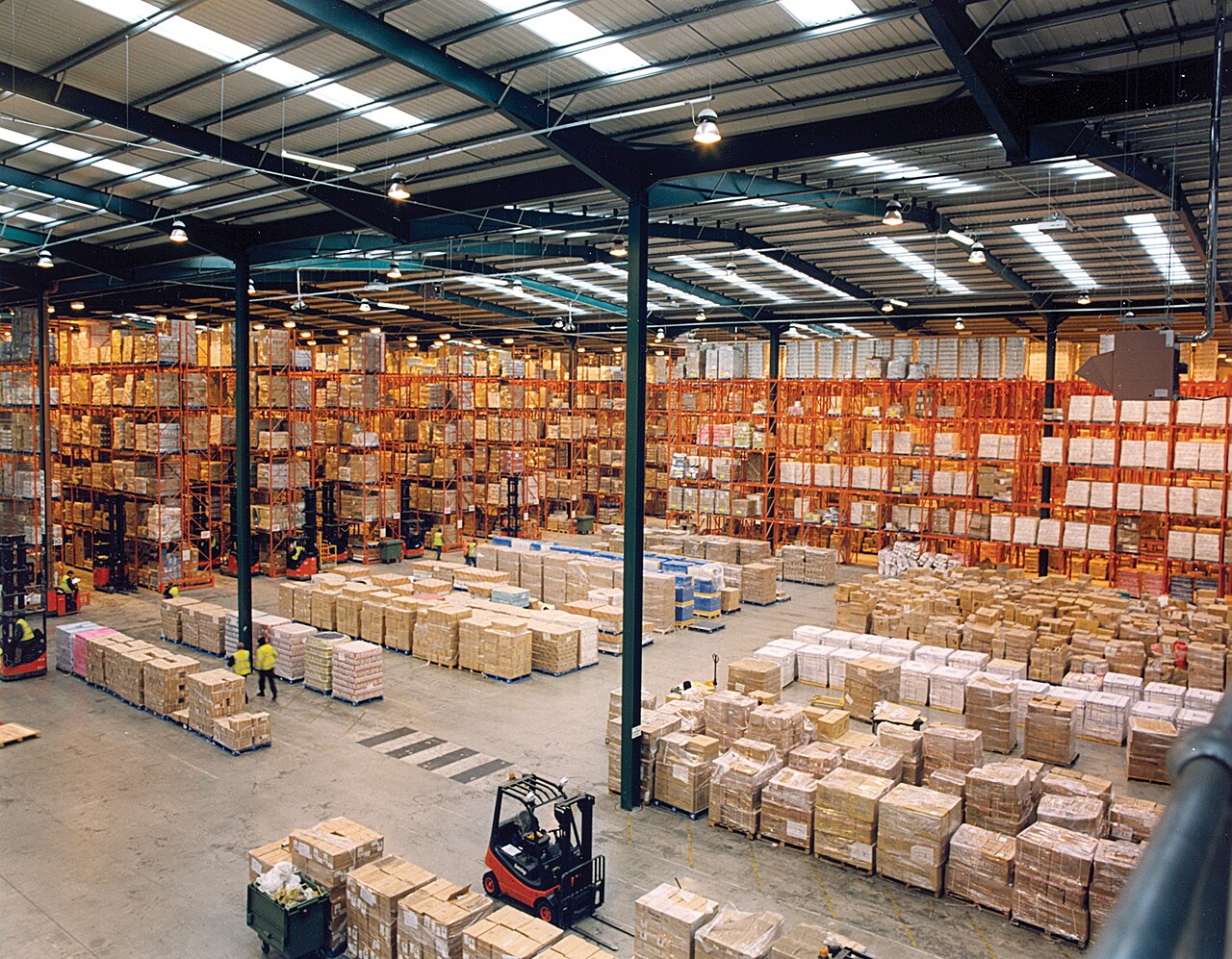 Modern magazijn met hoge palletstellingen en brede gangen, het soort omgeving waarin een magazijnbeheer-app locaties en goederenstroom aanstuurt