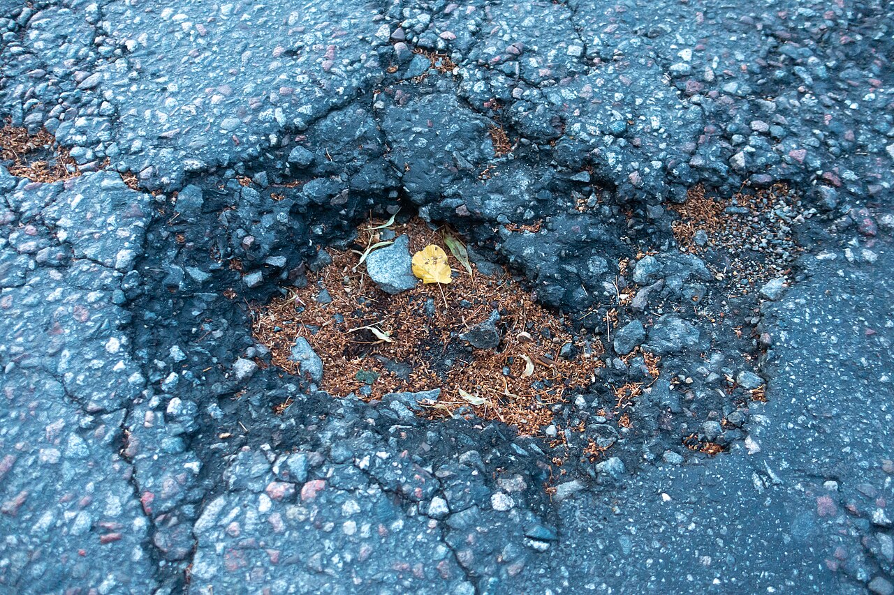 Kuil in het asfalt van een straat, het soort gebrek in de openbare ruimte dat een inwoner met een foto en locatie via een meldingsapp doorgeeft