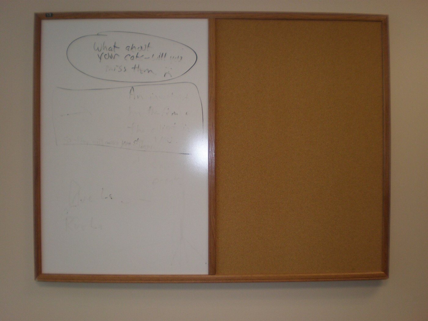 Een leeg whiteboard naast een prikbord aan een kantoormuur.