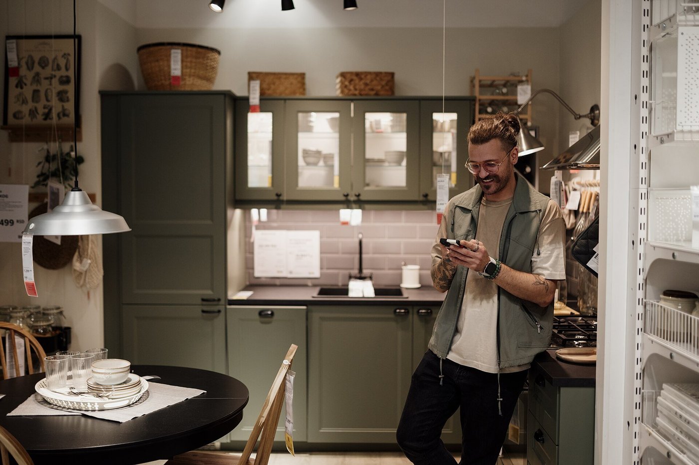 Een man in een keukenshowroom kijkt lachend op zijn telefoon.