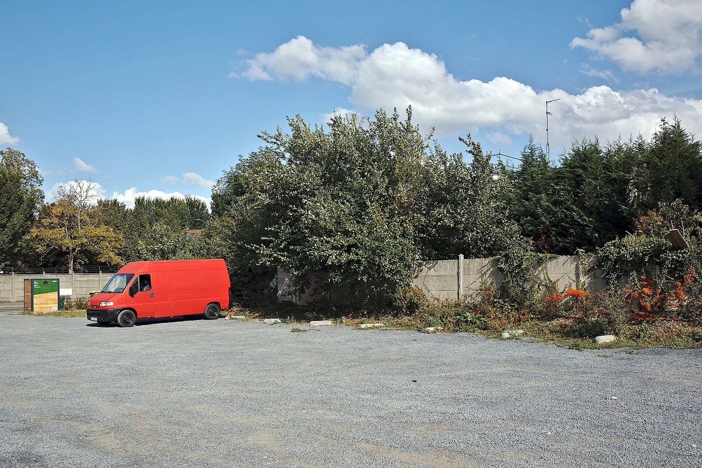 Een rode bestelwagen op een verlaten parkeerterrein.