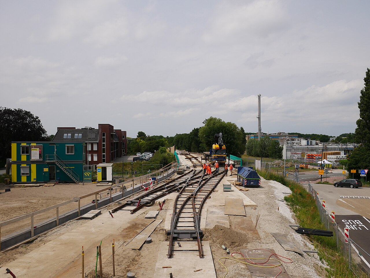 Overzicht van een infra-bouwplaats met spooraanleg, keten en werkers in veiligheidskleding