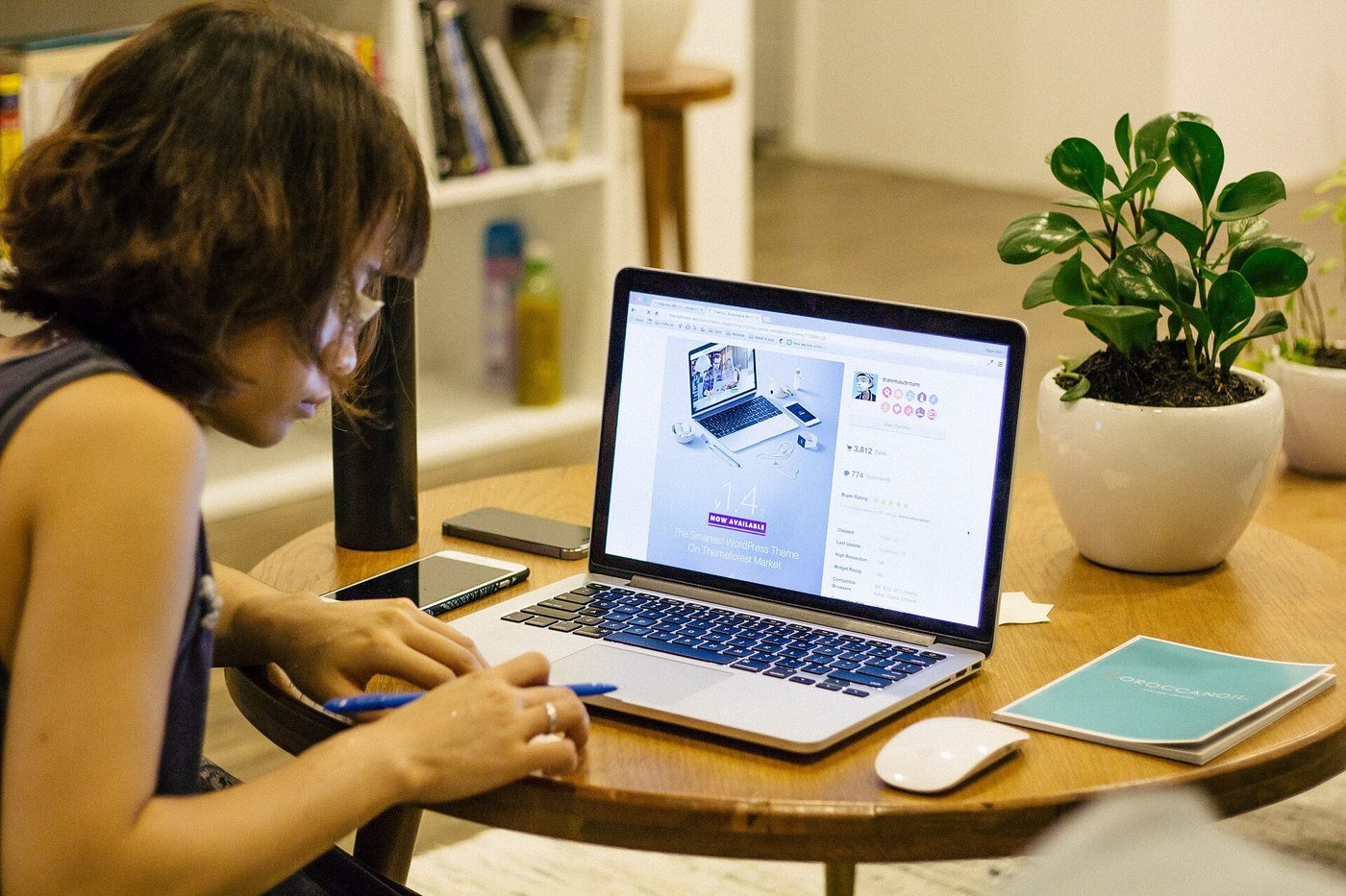 Iemand werkt aan een laptop en maakt aantekeningen aan een tafel.