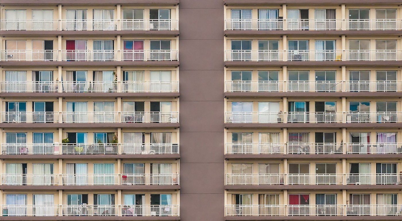 De gevel van een woonblok met rijen balkons boven elkaar.