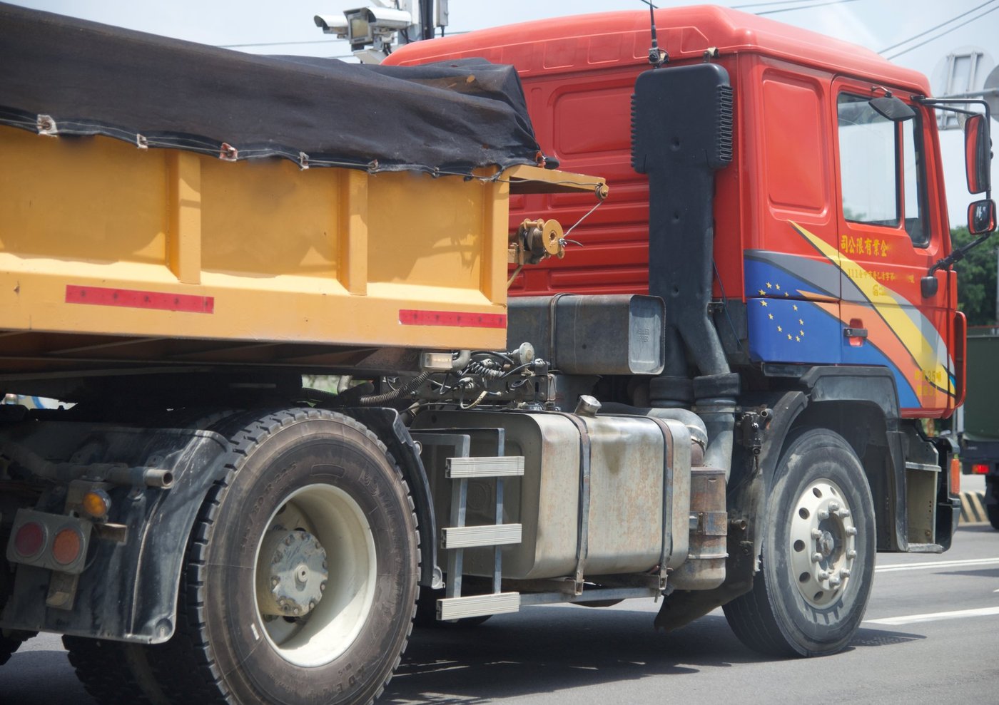 Een rode vrachtwagen met kipperbak op een weg, van dichtbij gezien.