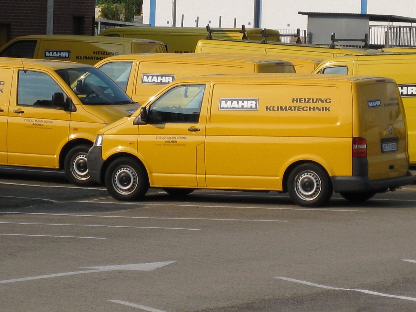 Een rij gele bedrijfsbussen van een installatiebedrijf op een parkeerterrein.