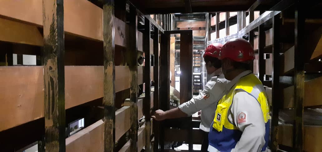 Medewerker met veiligheidsuitrusting werkt in een besloten ruimte onder begeleiding